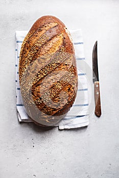 Top view of artisanal sesame seed bread on a napkin. Gray background