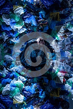 Top view of a artistic picture of a young man in studio, surrounded by empty plastic garbage bags