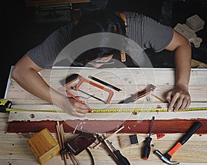 Top View of Asian Carpenter Working in Woodworking Workshop. Making Line with Ruler and Pencil on Planks of Wood