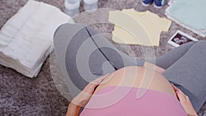 Top view Asian pregnant woman preparing diaper,feeding bottle for baby at home.Pregnant woman packing baby stuff ready for the