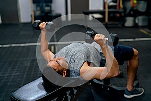 Top view of Asian sport man lift dumbells up to over head during exercise and lie on long chair in fitness gym