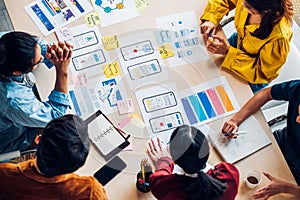 Top view asian ux developer and ui designer brainstorming about mobile app interface wireframe design on table with customer brief