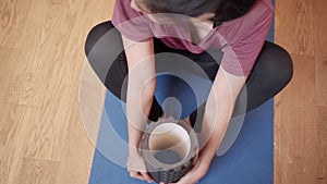 Top view Asian woman doing leg stretching on floor exercise mat in her apartment living room, sport equipment foam roller