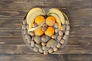 Top view of assorted fruit and dried fruits forming a heart on a dark wood background. Healthy eating and wellness concept