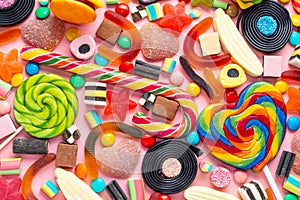 Top view of assortment colourful lollipops and candies on pink like background,  close up