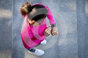 Top view of athletic african woman looking at her smartwatch