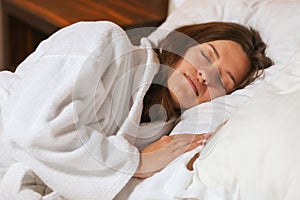 Top view of attractive young woman sleeping well in bed hugging soft white pillow. Teenage girl resting, good night sleep concept.