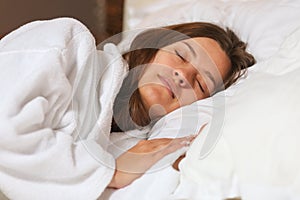 Top view of attractive young woman sleeping well in bed hugging soft white pillow. Teenage girl resting, good night sleep concept.