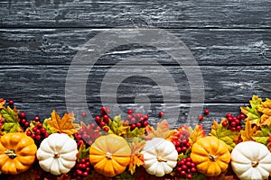 Top view of Autumn maple leaves with Pumpkin and red berries on old wooden backgound.