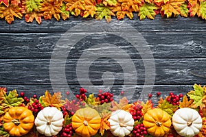 Top view of Autumn maple leaves with Pumpkin and red berries on old wooden backgound.