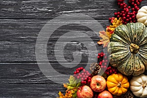 Top view of Autumn maple leaves with Pumpkin and red berries on old wooden backgound.