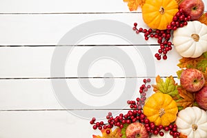 Top view of Autumn maple leaves with Pumpkin and red berries on old wooden backgound.