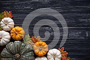 Top view of Autumn maple leaves with Pumpkin and red berries on old wooden backgound.