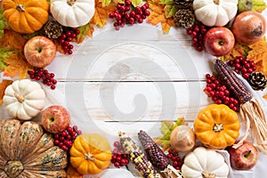 Top view of Autumn maple leaves with Pumpkin and red berries on old wooden backgound.