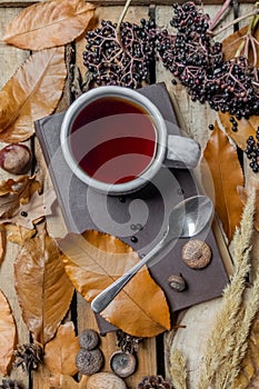 Top view autumn still life composition a cup of tea with spoon on brown book, on wooden old  boards with autumn leaves and
