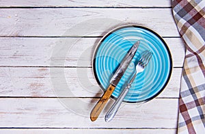 Top view background with empty blue ceramic plate, antique silver cutlery on vintage weathered white wooden boards