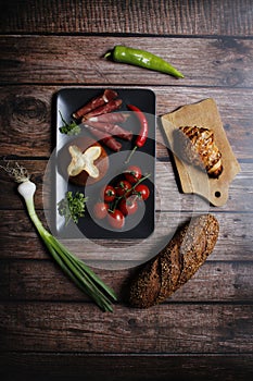 Top view of bacon rolls with fresh vegetables, croissant, and bread on a kitchen table