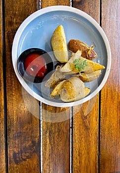 Top View Baked potato wedges with shredded onion and herbs and tomato sauce