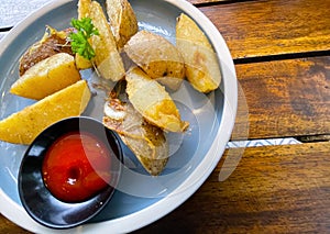 Top View Baked potato wedges with shredded onion and herbs and tomato sauce