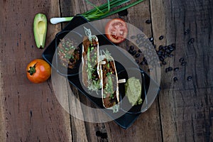 Top view of baked tortillas with black beans, tomato, cilantro, red onion, avocado and assorted spices served with avocado dip