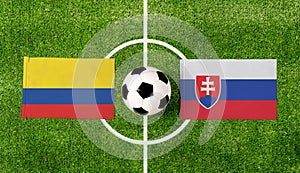 Top view ball with Colombia vs. Slovakia flags match on green football field