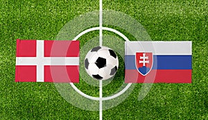 Top view ball with Denmark vs. Slovakia flags match on green football field