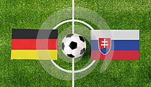 Pohľad zhora na loptu s vlajkami Nemecko vs. Slovensko na zelenom futbalovom ihrisku