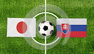 Pohľad zhora na loptu s vlajkami Japonska vs. Slovensko na zelenom futbalovom ihrisku