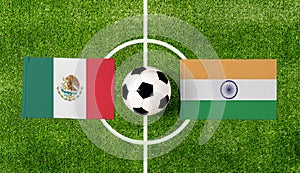 Top view ball with Mexico vs. India flags match on green football field