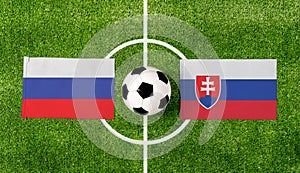 Pohľad zhora na loptu s vlajkami Rusko vs. Slovensko na zelenom futbalovom ihrisku