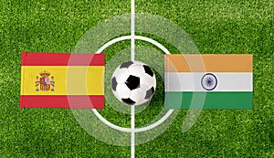 Top view ball with Spain vs. India flags match on green soccer field