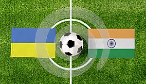 Top view ball with Ukraine vs. India flags match on green football field