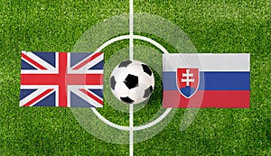 Pohľad zhora na loptu s vlajkami Spojeného kráľovstva vs. Slovensko na zelenom futbalovom ihrisku