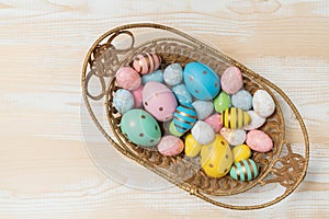 Top view of basket with colorful Easter eggs. Wooden background