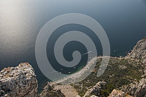 Top view of a bay and white boats. On the edge of a cliff high above the sea.