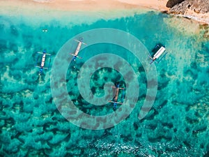Top view of beach with turquoise sea water and local boats, aerial shot