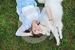 Top view of beaming woman lying near her white dog