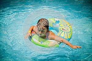 Top view of beautiful child girl in swimming pool relax swim on inflatable ring