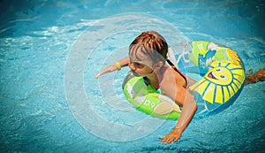 Top view of beautiful child girl in swimming pool relax swim on inflatable ring. Summer holiday, vacation and happy childhood.