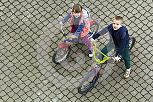 Top view of beautiful children brother and sister riding bicycles on cool spring day looking upward. Outdoors activities.healthy l