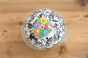 Top view beautiful Easter cakes in white glaze and decorations with culinary flowers on a wooden table