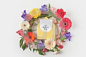 top view of beautiful floral wreath and happy mothers day greeting card in envelope on grey