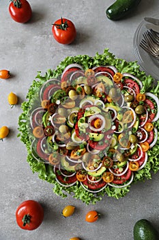 Top view of beautiful Mandala like fresh tomato, avocado, olives, lettuce and onion salad garnished with spring onion & nigella se