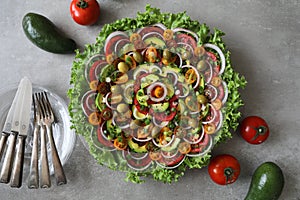 Top view of beautiful Mandala like fresh tomato, avocado, olives, lettuce and onion salad garnished with spring onion & nigella se