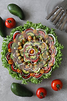 Top view of beautiful Mandala like fresh tomato, avocado, olives, lettuce and onion salad garnished with spring onion & nigella se