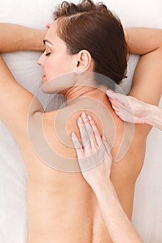 Top view of a beautiful model girl lying and hands of a masseuse doing back massage. Studio photography on a white background for