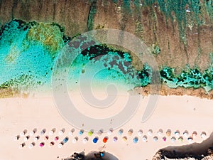 Top view of beautiful sand beach with turquoise ocean water and colorful umbrellas, aerial drone shot
