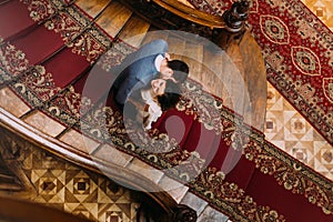 Top view on beautiful young bride and handsome groom kissing at old stairs with the background of gorgeous wooden