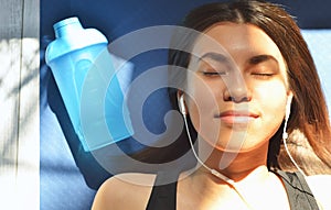 Top view of beautiful young girl in headphones listening to music while lying on yoga mat