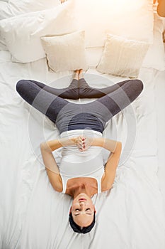 Top view on beautiful young woman lying on bed, in shavasana pose
